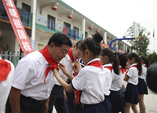 學生為領(lǐng)導系紅領(lǐng)巾表達感恩之心